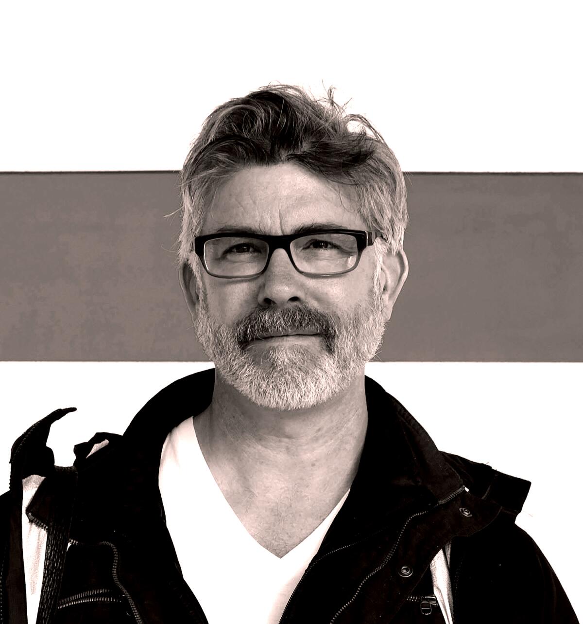 Author Laird Hunt wearing a white T-shirt, a jacket and glasses