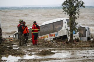 Rescuers stand next to a bus carried away after heavy rainfall triggered landslides that collapsed buildings and left as many as 12 people missing, in Casamicciola, on the southern Italian island of Ischia, Italy, Saturday, Nov. 26, 2022. Firefighters are working on rescue efforts as reinforcements are being sent from nearby Naples, but are encountering difficulties in reaching the island either by motorboat or helicopter due to the weather. (AP Photo/Salvatore Laporta)