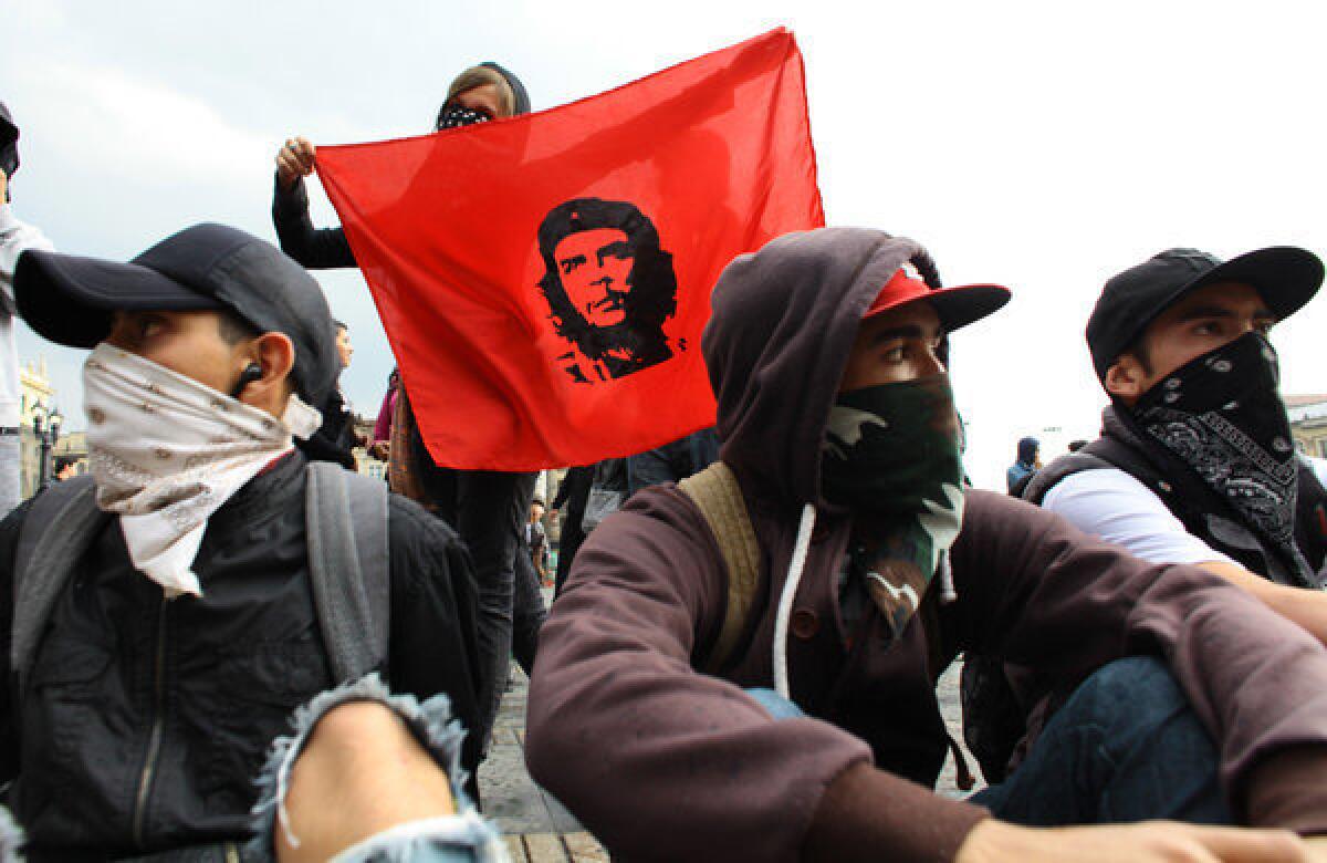 Masked protesters attend a march in Bogota, Colombia, demanding to participate in the government's peace talks with the rebels of the Revolutionary Armed Forces of Colombia, or FARC. One holds an image of Cuba's revolutionary hero Ernesto "Che" Guevara.