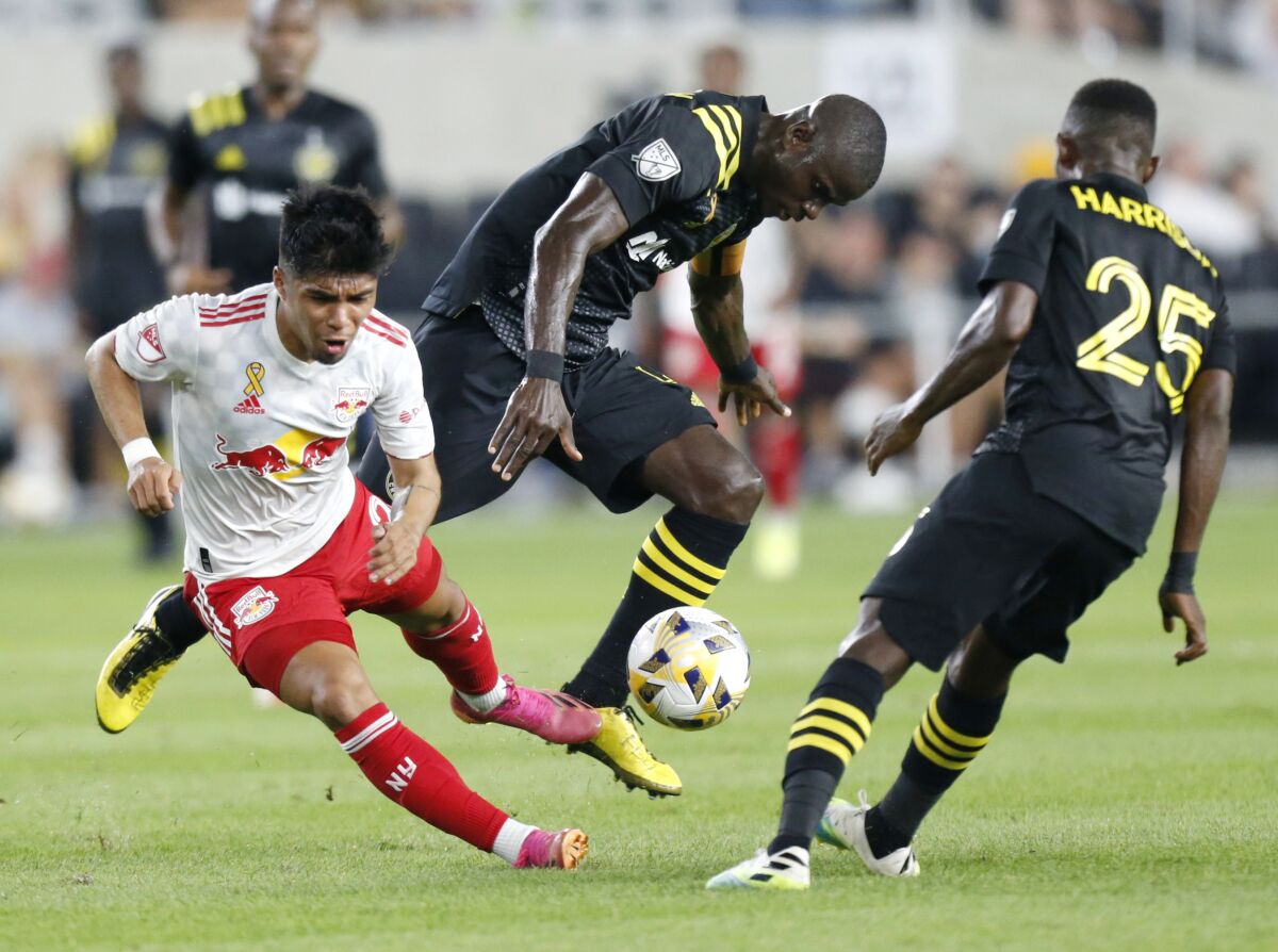 Columbus Crew defender Jonathan Mensah, center, collides with New York Red Bulls midfielder Omir Fernandez, left, in front of Crew defender Harrison Afful during the first half of an MLS soccer match in Columbus, Ohio, Tuesday, Sept. 14, 2021. Mensah was called for a penalty on the play. (AP Photo/Paul Vernon)