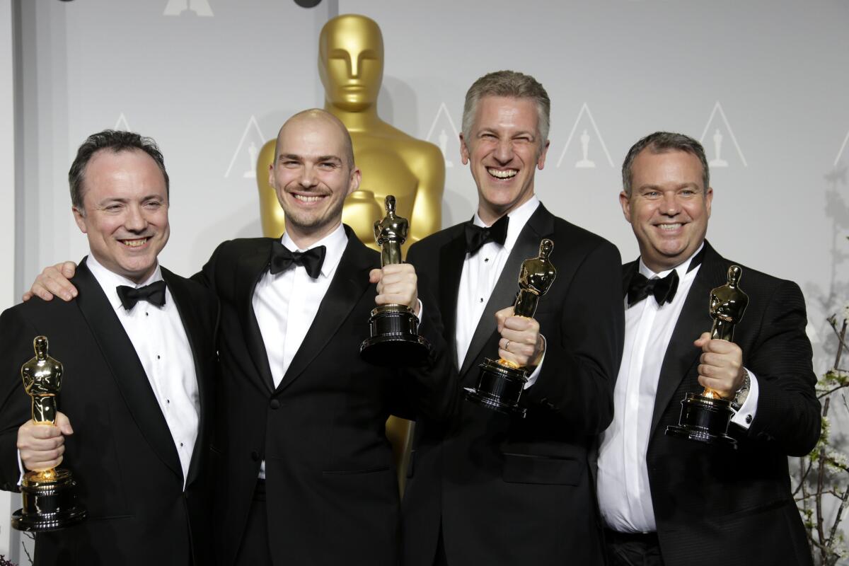 From left, Tim Webber, Chris Lawrence, Dave Shirk and Neil Corbould grip their Oscars for best visual effects during the 86th annual Academy Awards on March 2, 2014.