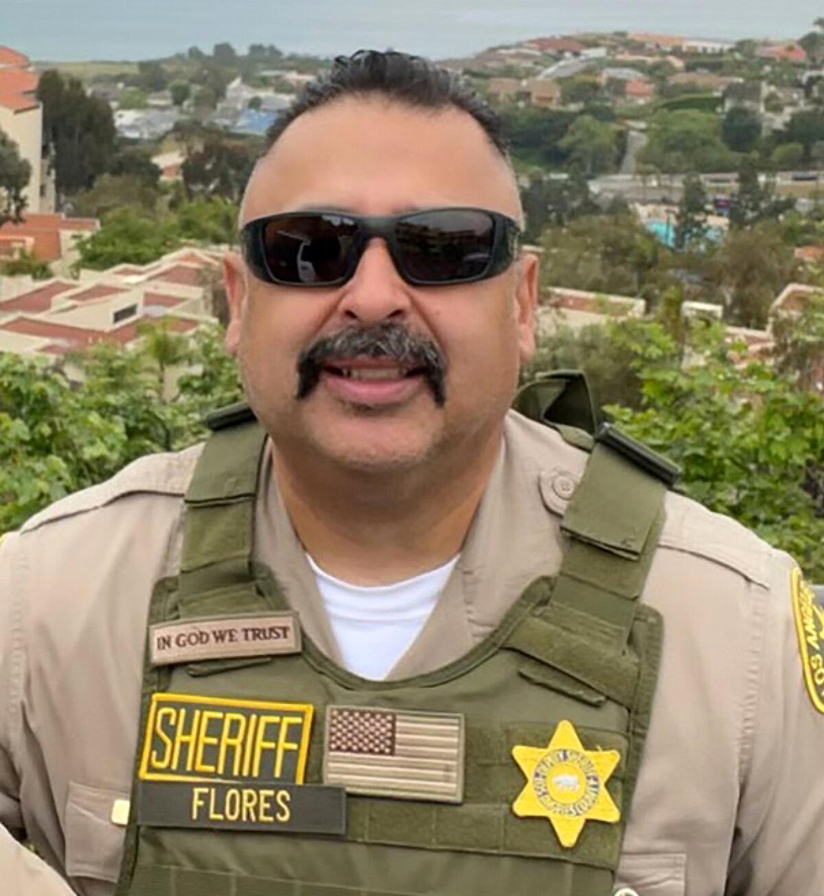 Portrait of late sheriff's Deputy Alfredo "Freddy" Flores wearing sunglasses and a vest with a badge and his name