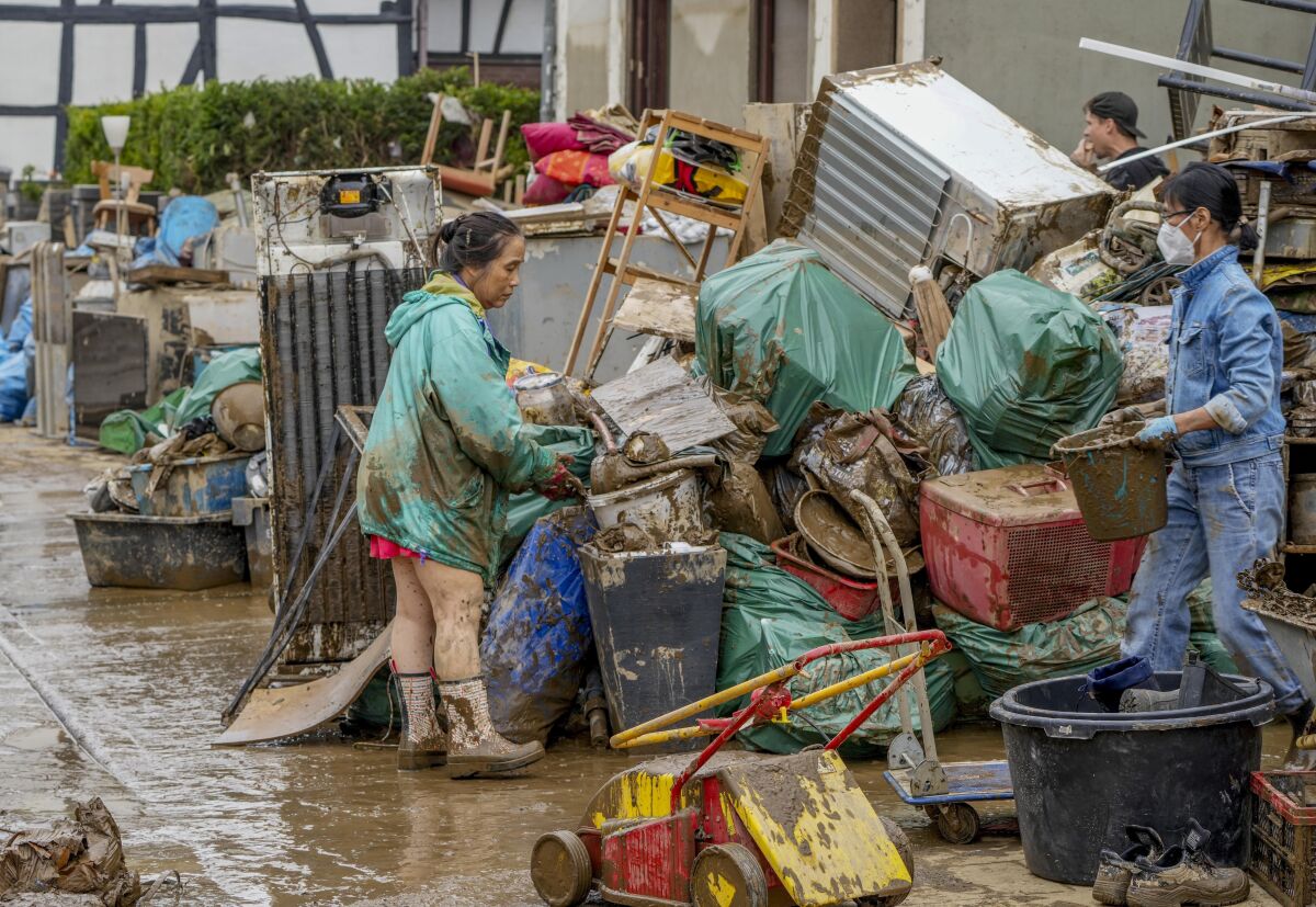 FILE-People clean their homes from mud and debris in Bad Neuenahr-Ahrweiler, Germany, Saturday, July 17, 2021. Hundreds of thousands of tons of junk have been removed from a valley in western Germany since it was devastated by flooding in mid-July, equivalent to four decades' worth of garbage, authorities said Friday. (AP Photo/Michael Probst, file)