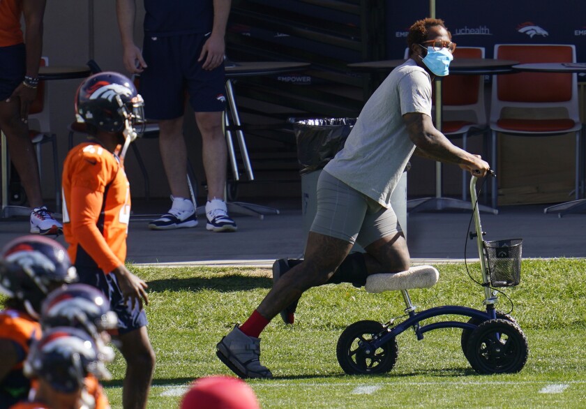 Injured Denver Broncos outside linebacker Von Miller uses a scooter to maneuver around as his teammates warm up before taking part in drills during an NFL football practice Wednesday, Oct. 14, 2020, at the team's headquarters in Englewood, Colo. (AP Photo/David Zalubowski)