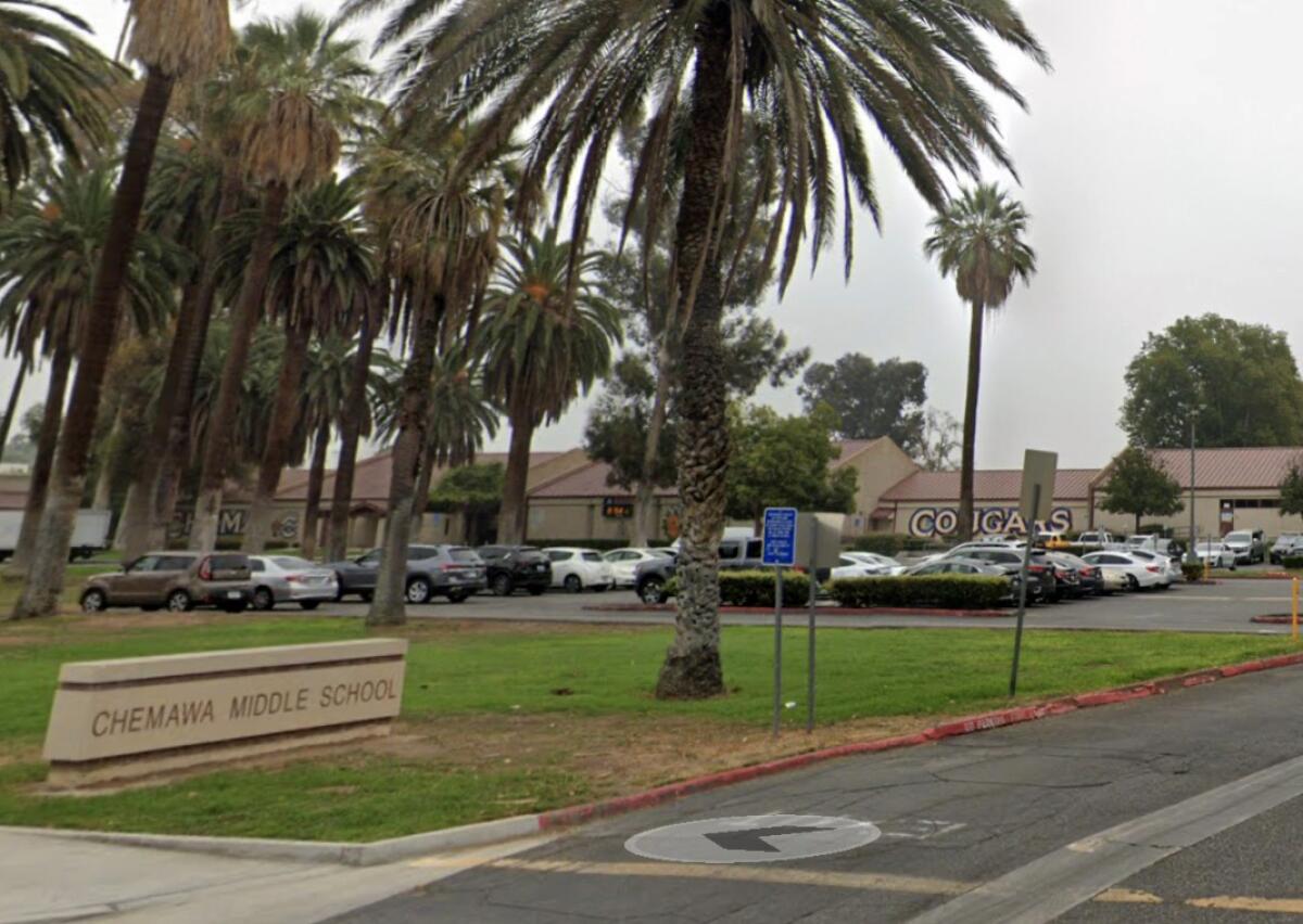 A parking lot full of cars next to a lawn with a sign that says "Chemawa Middle School."