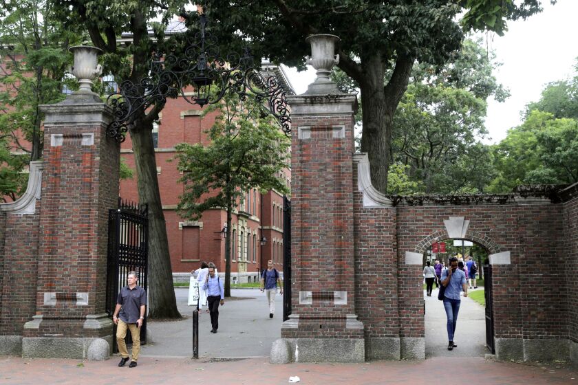 FILE - In this Aug. 13, 2019, file photo, pedestrians walk through the gates of Harvard Yard at Harvard University in Cambridge, Mass. Harvard and the Massachusetts Institute of Technology filed a federal lawsuit Wednesday, July 8, 2020, challenging the Trump administration's decision to bar international students from staying in the U.S. if they take classes entirely online this fall. Some institutions, including Harvard, have announced that all instruction will be offered remotely in the fall during the ongoing coronavirus pandemic. (AP Photo/Charles Krupa, File)