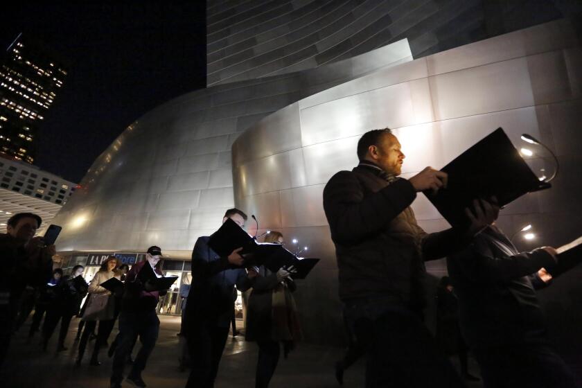 LOS ANGELES CA - FEBRUARY 7, 2020 - Members of the Los Robles Master Chorale walk along Grands Avenue while giving a free public performance of Weimar Variations, “Workers Chorus,” protest songs in front of the Walt Disney Concert Hall in downtown Los Angeles on February 7, 2020. (Genaro Molina / Los Angeles Times)