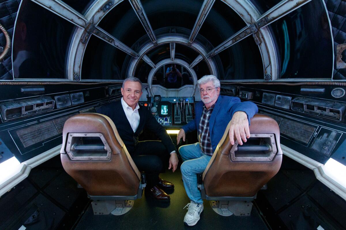 El presidente de Disney, Bob Iger, y el cineasta George Lucas posan al interior de "Millennium Falcon: Smugglers Run" en "Star Wars: Galaxy's Edge" de Disneyland.