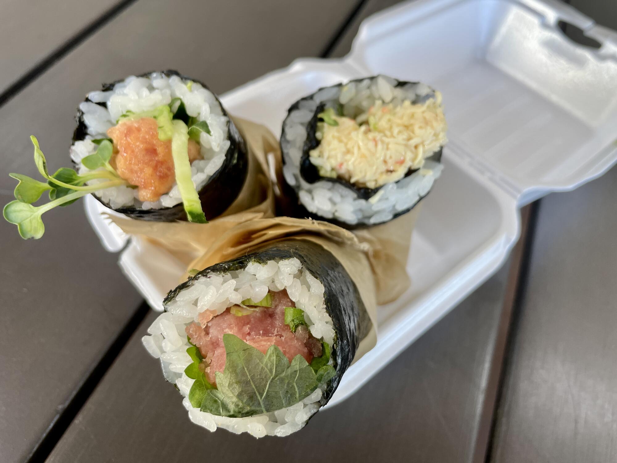 three hand rolls in a a takeout container 