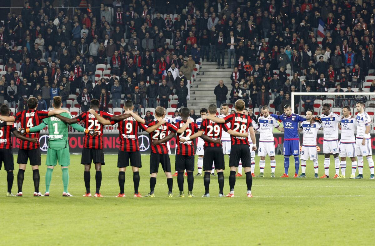 Jugadores del Niza (i), y Lyon guardan un minuto de silencio previo a un partido de la liga francesa en Niza.
