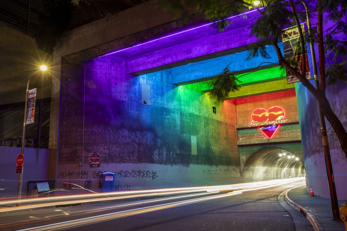 Neon lights in pastel shades illuminate a city traffic tunnel, with a red heart in neon that says "Los Angeles."