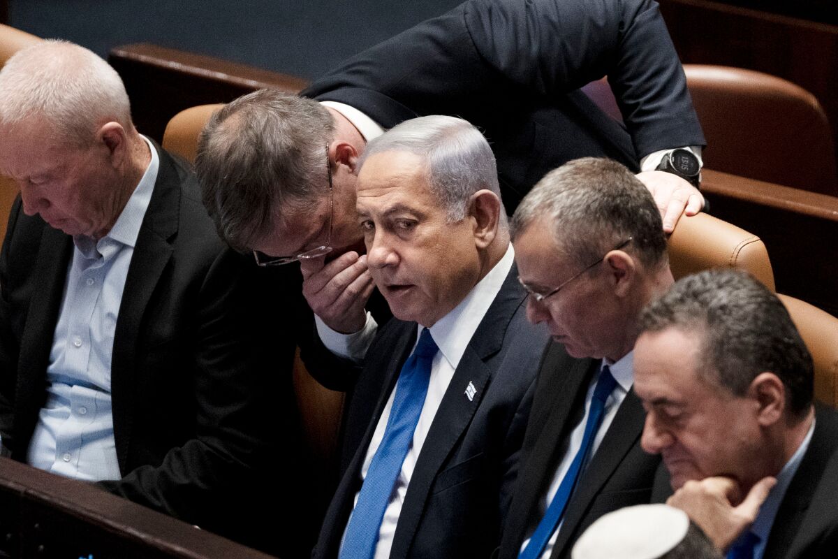 Lawmakers surround Israel's Prime Minister Benjamin Netanyahu, center, at a session of the Knesset, Israel's parliament