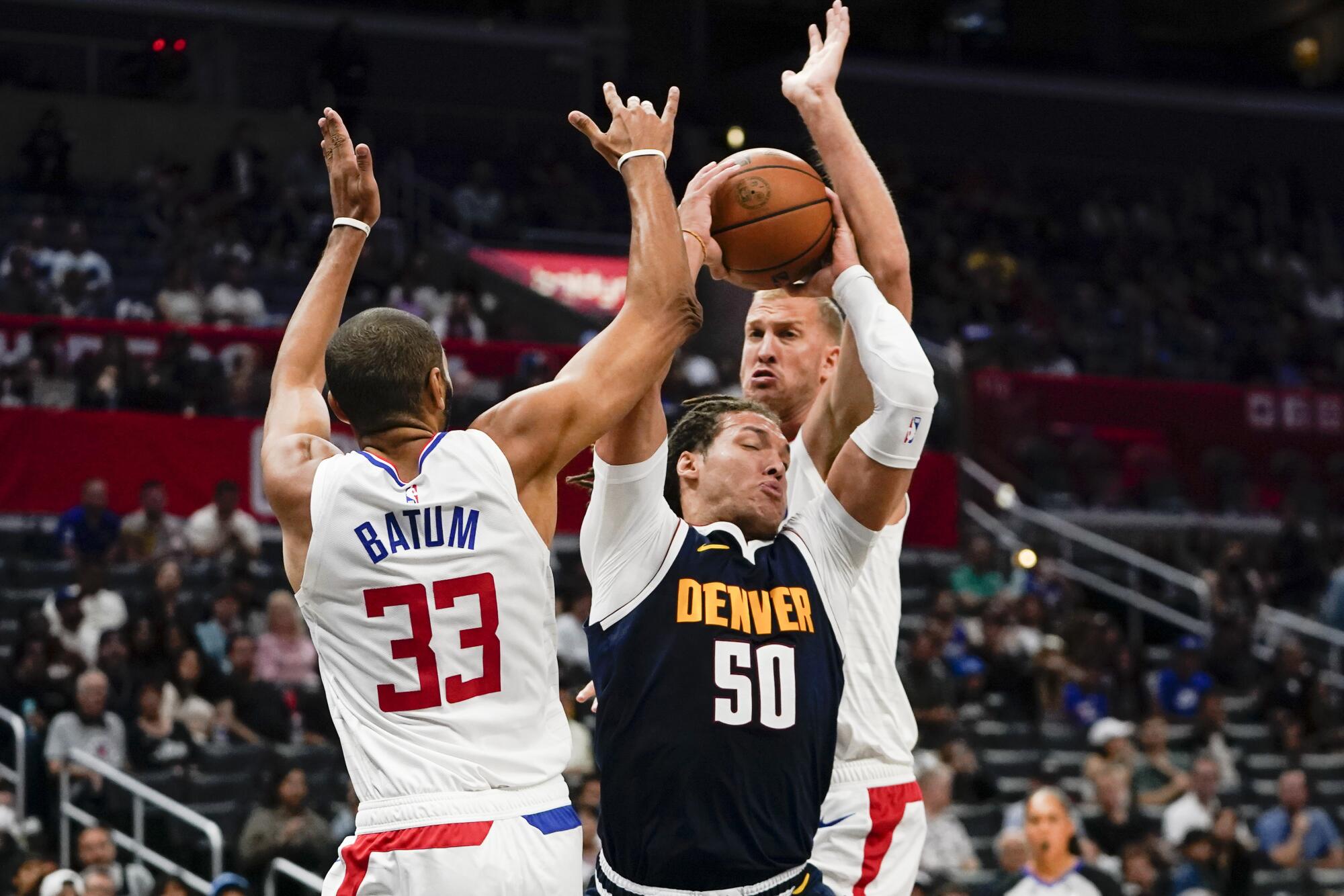 Clippers center Ivica Zubac, back right, and forward Nicolas Batum swarm Nuggets forward Aaron Gordon in the lane.