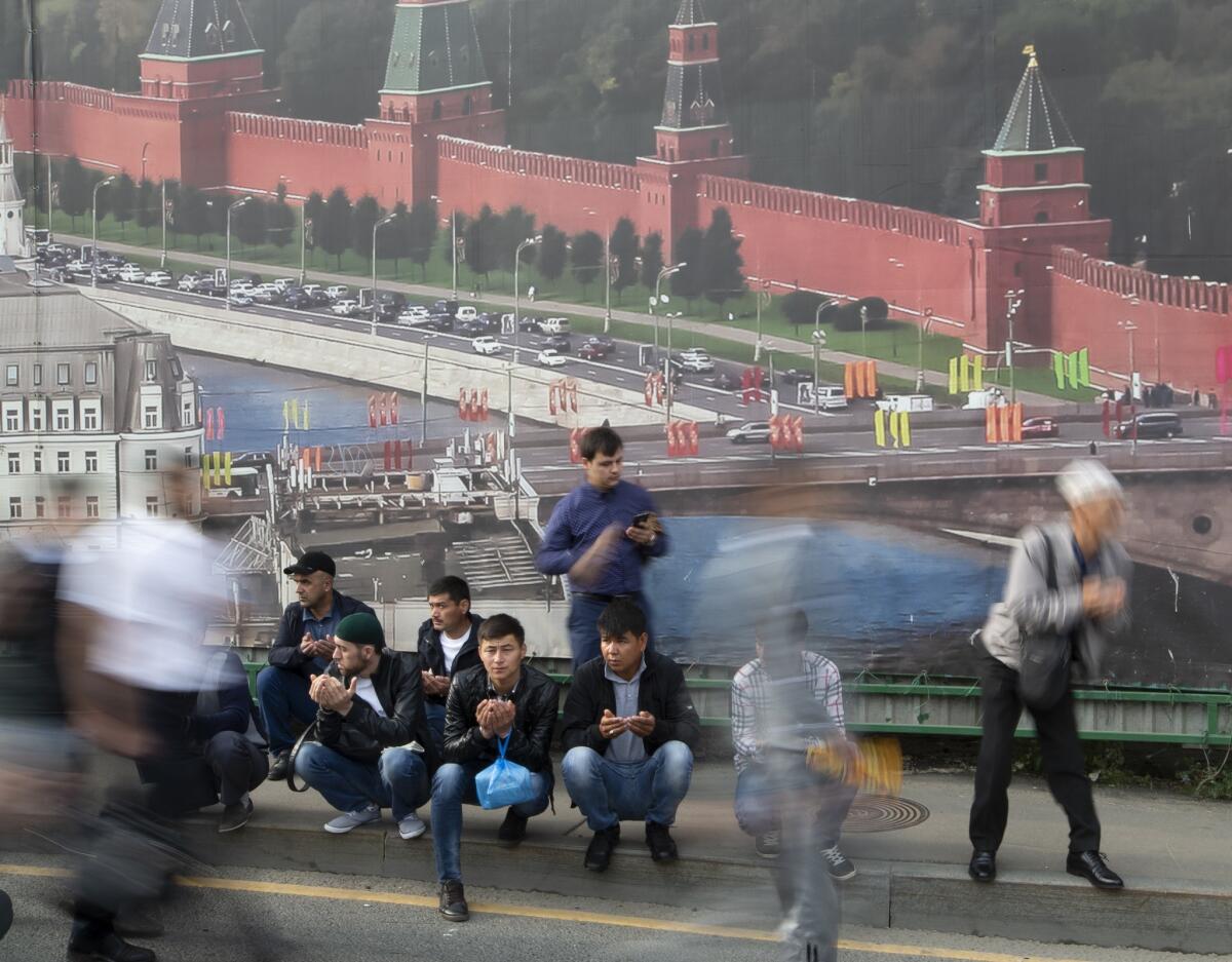 Russia: Muslims sit in front of a huge poster showing the Kremlin as they arrive for prayers outside the Moscow Cathedral Mosque during celebrations of Eid al-Adha.