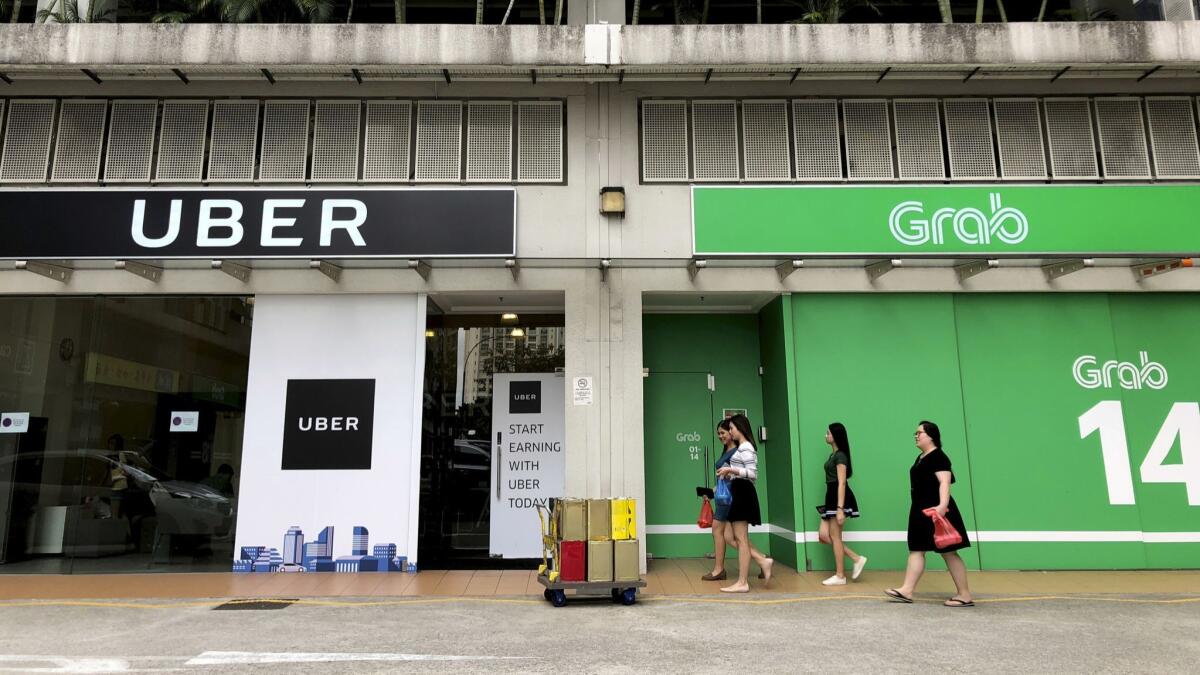 People walk past Uber and Grab offices in Singapore.
