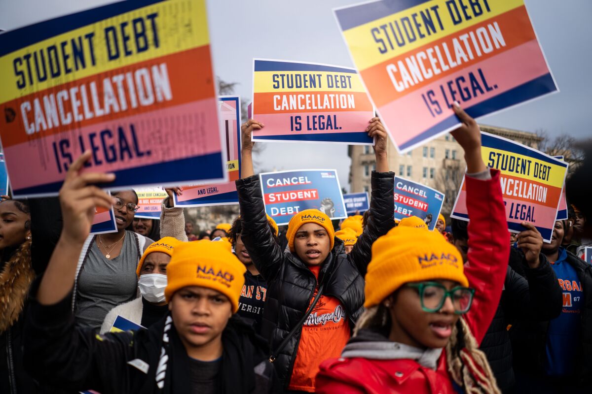 A large group of people holding signs that read "Student debt cancellation is legal" 
