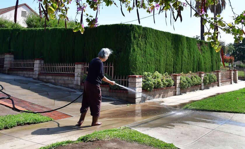 A woman wades down her driveway in Monterey Park
