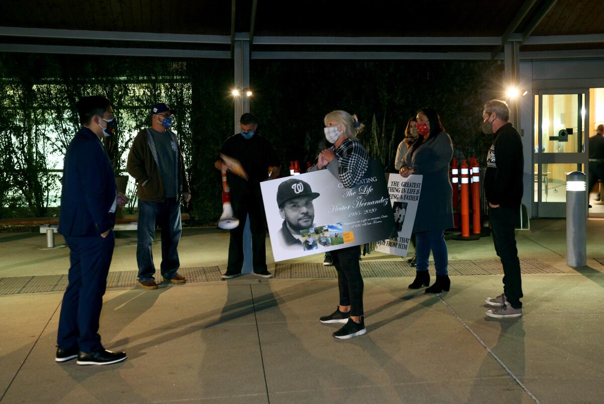 People stand outside the Fullerton Community Center with posters of Hector Hernandez.