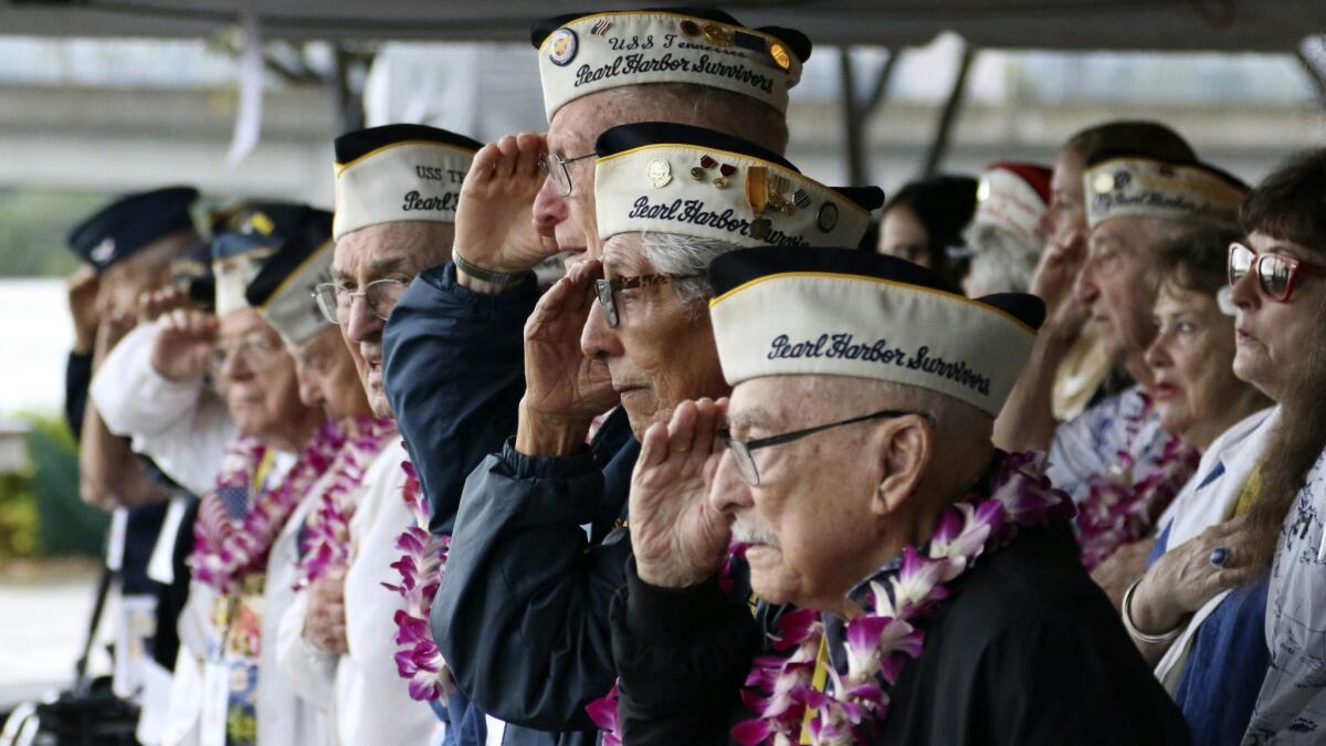 Pearl Harbor survivors salute during the national anthem at a ceremony in Pearl Harbor, Hawaii, on Friday. The event marked the 77th anniversary of the attack.