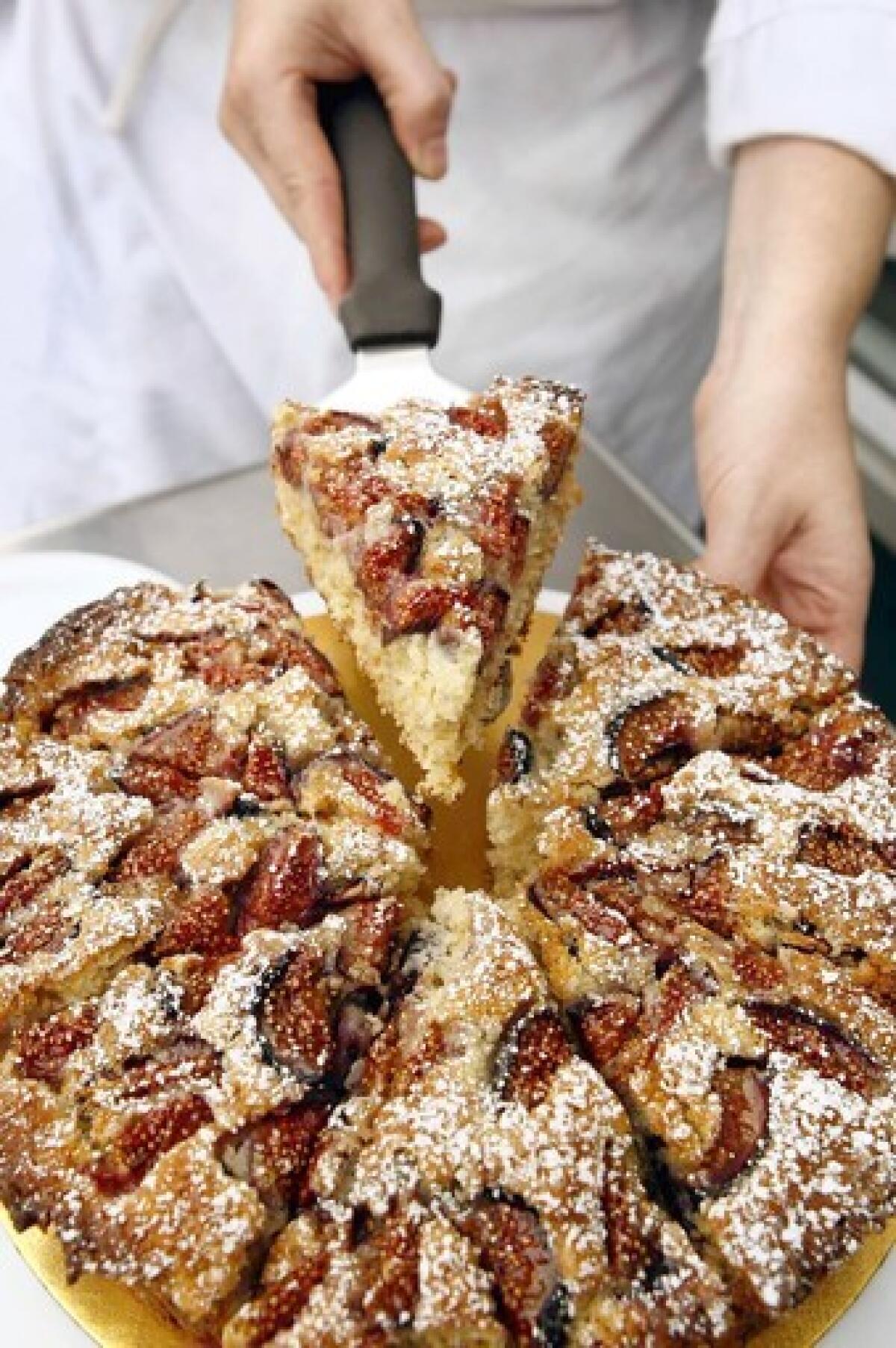 The rolled-oat cake with figs is sliced into servings at Proof Bakery in Atwater Village. Recipe