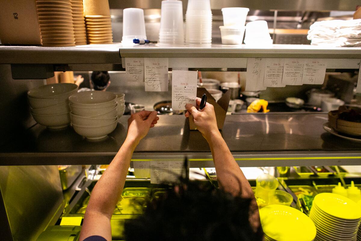 A chef looks at tickets on the pass in the kitchen of a restaurant.