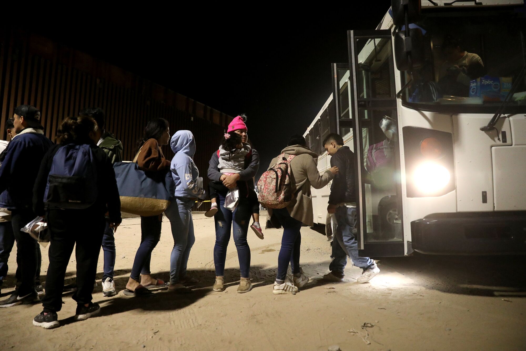Immigrants are lined up to board a bus after turning themselves over to U.S Border Patrol agents.