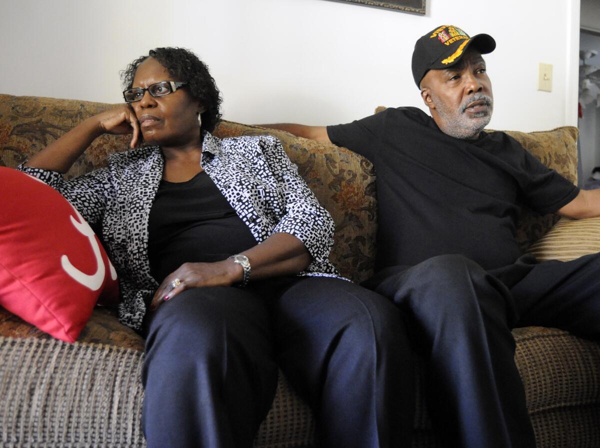 A woman and a man sit on a couch.