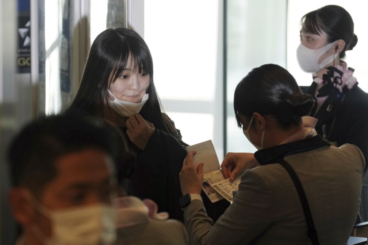 Japan's former Princess Mako, left, the elder daughter of Crown Prince Akishino, takes her mask off at a boarding gate to board an airplane to New York with her husband Kei Komuro, not in picture, Sunday, Nov. 14, 2021, at Tokyo International Airport in Tokyo. (AP Photo/Eugene Hoshiko)