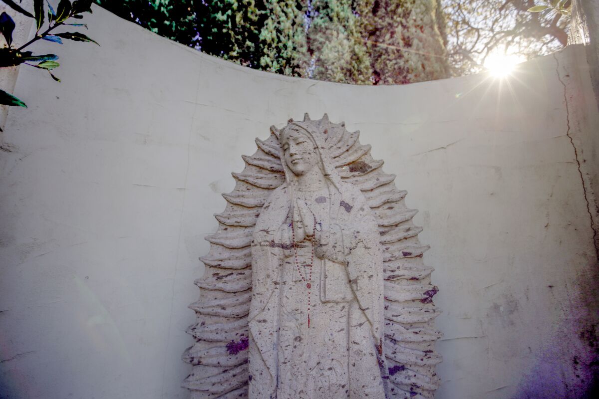 A monochrome white statue of Our Lady of Guadalupe
