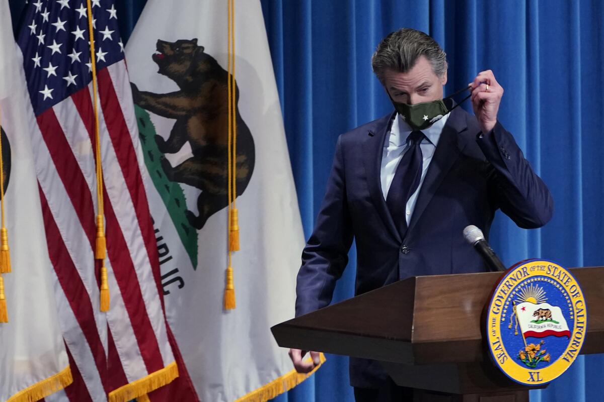 Gov. Gavin Newsom removes his face mask before speaking at a news conference in Sacramento in January. 