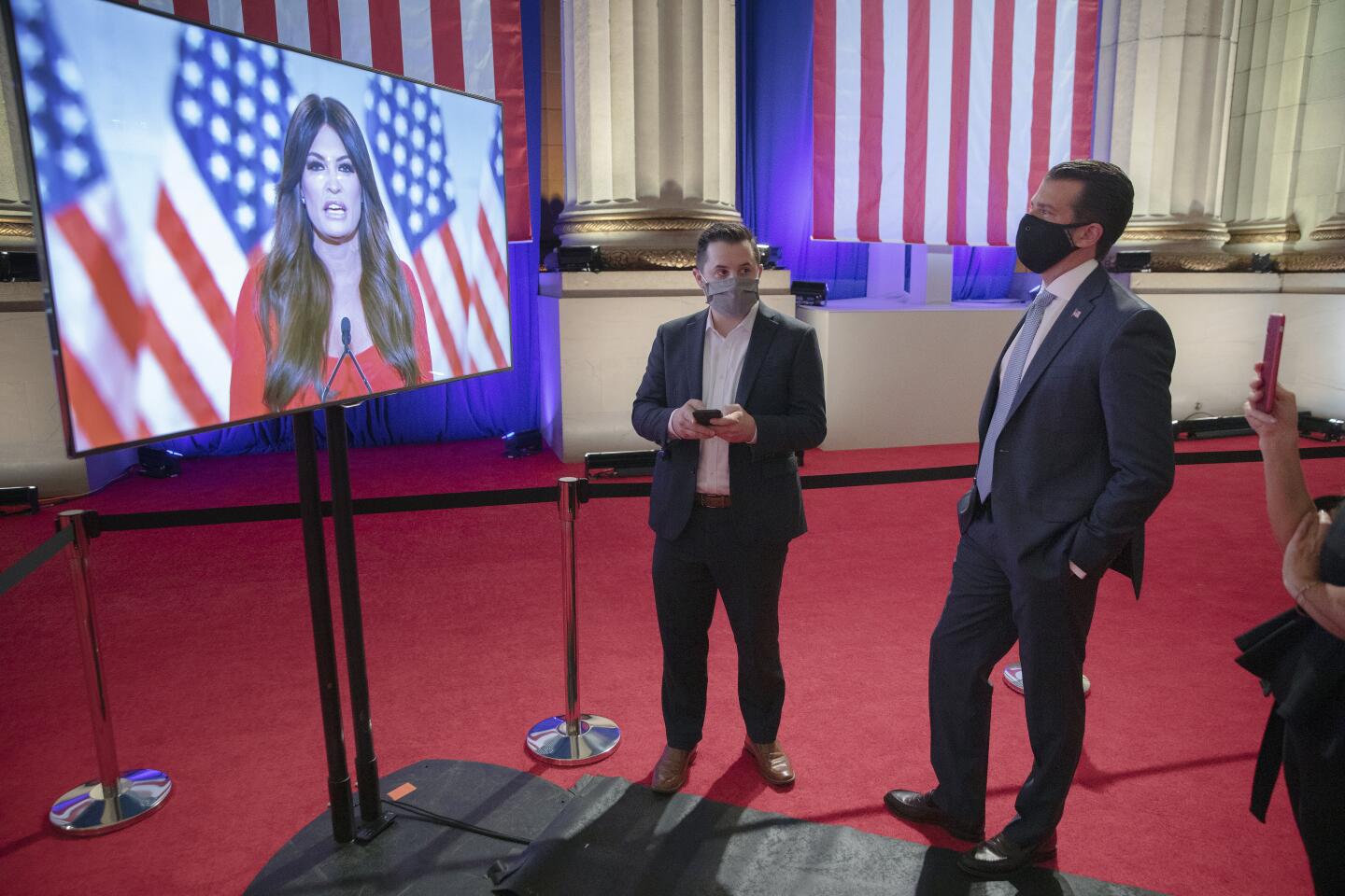 Donald Trump Jr., right, watches his girlfriend, Kimberly Guilfoyle, as she records her address to the convention.