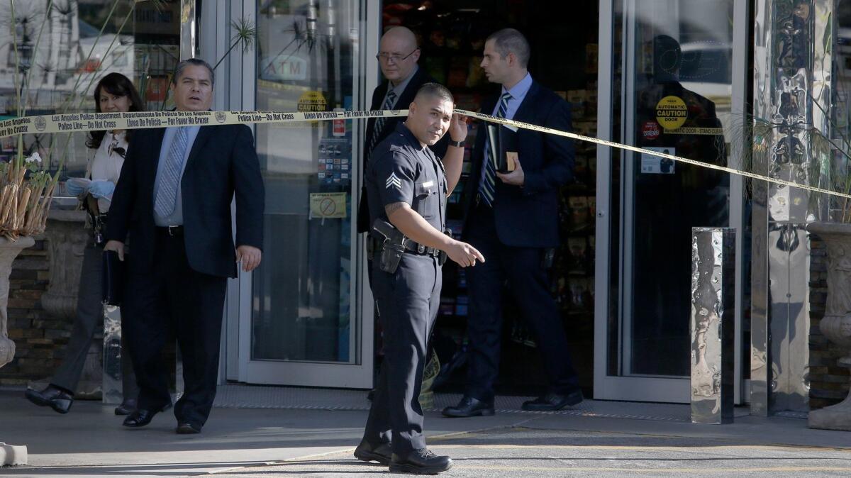 LAPD investigators emerge from the Chevron station mini-mart where a store clerk was shot to death during a robbery in the Los Feliz area.