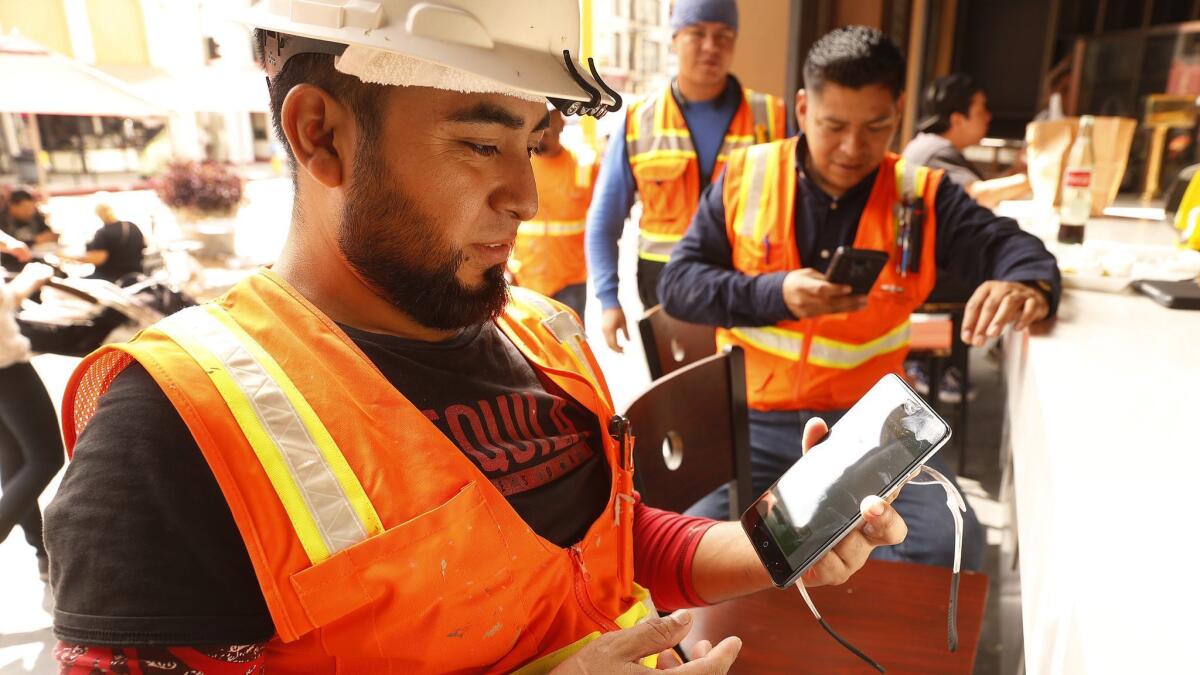 Christian Herrera, left, shows the alert message on his cell phone minutes following the 11:18 A.M. 'Presidential Alert' on Wednesday at Grand Central Market in downtown Los Angeles.