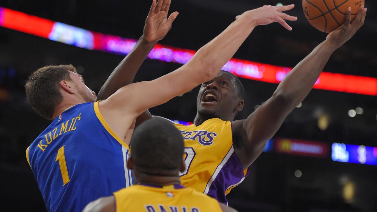 Lakers rookie forward Julius Randle, right, puts up a shot in front of Golden State Warriors center Ognjen Kuzmic during the first half of a preseason game Thursday.