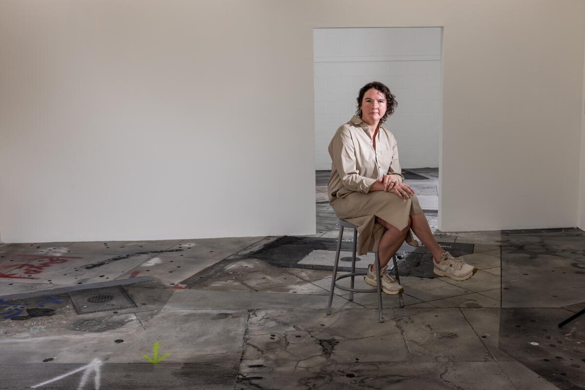 A woman sits on a metal stool in her art studio.