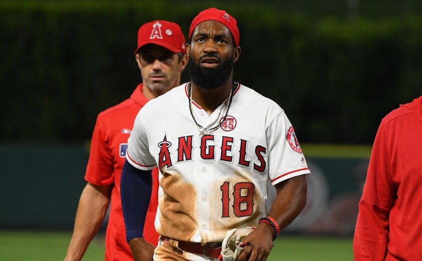 Angels Brian Goodwin is helped off the field after he injured his back diving into second base for a double in the second inning against the Houston Astros at Angel Stadium on Thursday.
