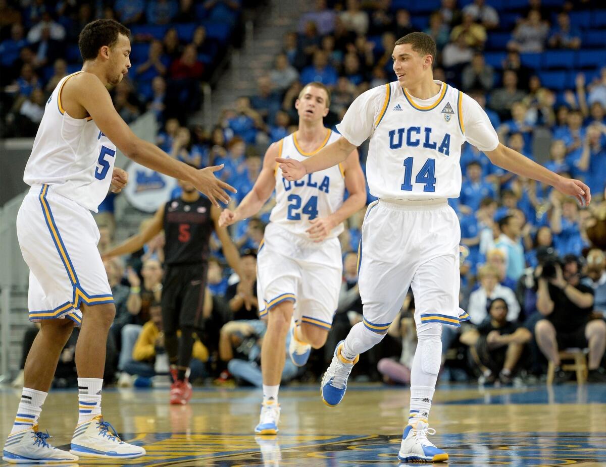 Zach LaVine, right, celebrates with Kyle Anderson, left, after dishing a pass to Travis Wear, back, for the score during UCLA's 91-74 win Thursday over Stanford at Pauley Pavilion.