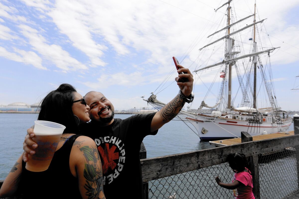 Jackie Gomez, left, and Eddie Tapia take a selfie at the San Pedro Fish Market. A planned development at neaerby Ports O' Call has owner Tommy Amalfitano concerned.