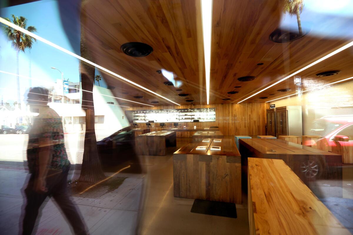 A reflection of a pedestrian in the window of a cannabis dispensary.