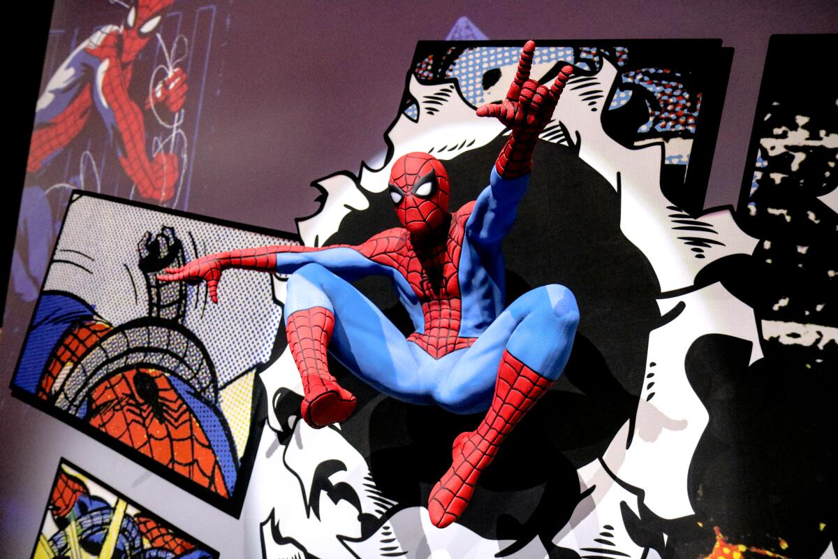 A spider-man figure strikes a spidey pose attached to a wall of comic illustrations