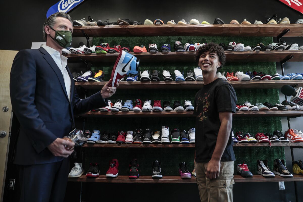 Gov. Gavin Newsom holds a sneaker while touring a shoe store