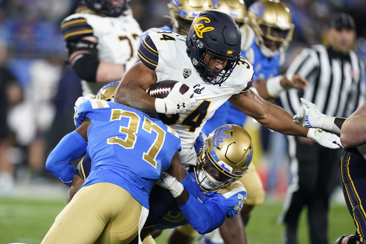 California running back Christopher Brooks is stopped by UCLA defensive back Quentin Lake and linebacker Carl Jones Jr.
