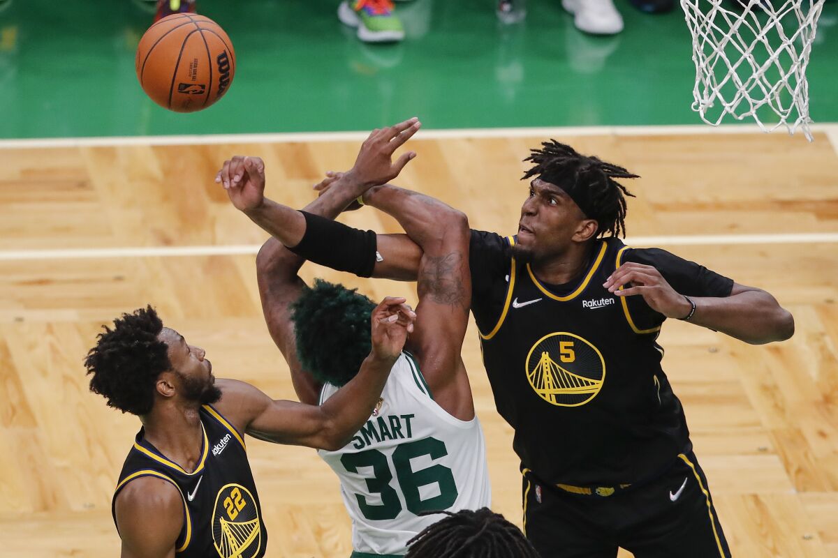 Golden State Warriors center Kevon Looney (5) and forward Andrew Wiggins (22) battle for a rebound against Boston Celtics guard Marcus Smart (36) during the fourth quarter of Game 4 of basketball's NBA Finals, Friday, June 10, 2022, in Boston. (AP Photo/Michael Dwyer)