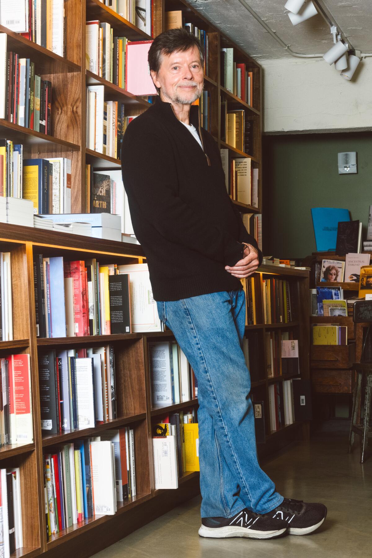 Ken Burns leaning against a filled bookcase in a New York bookstore.