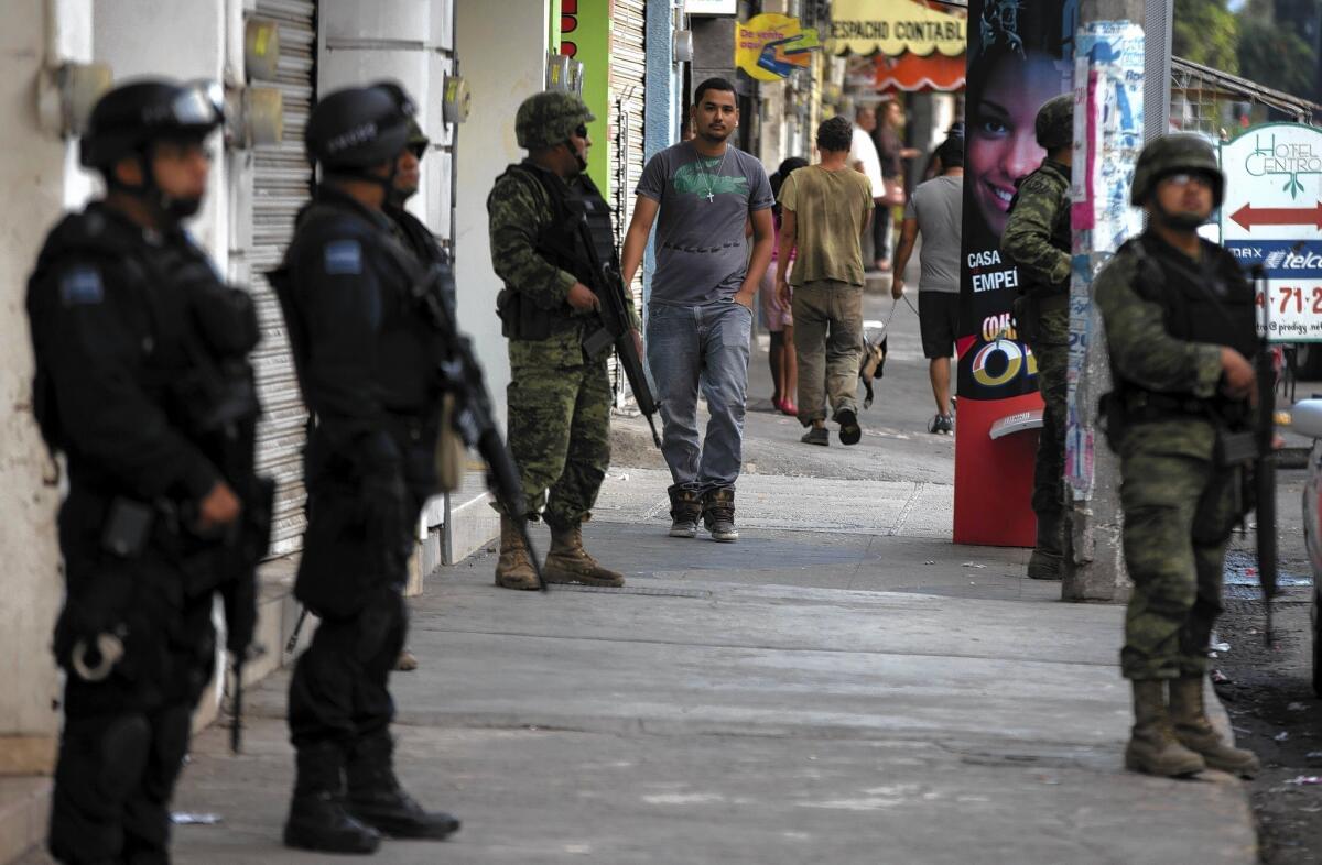 Mexican federal police and soldiers stand guard in Apatzingan, where vigilante groups have been trying to force out the Knights Templar drug cartel.