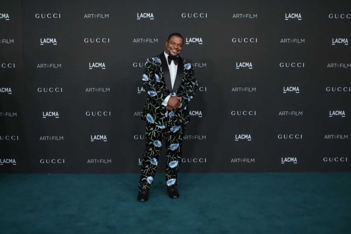 Kehinde Wiley in a dark suit decorated with a bright blue floral motif
