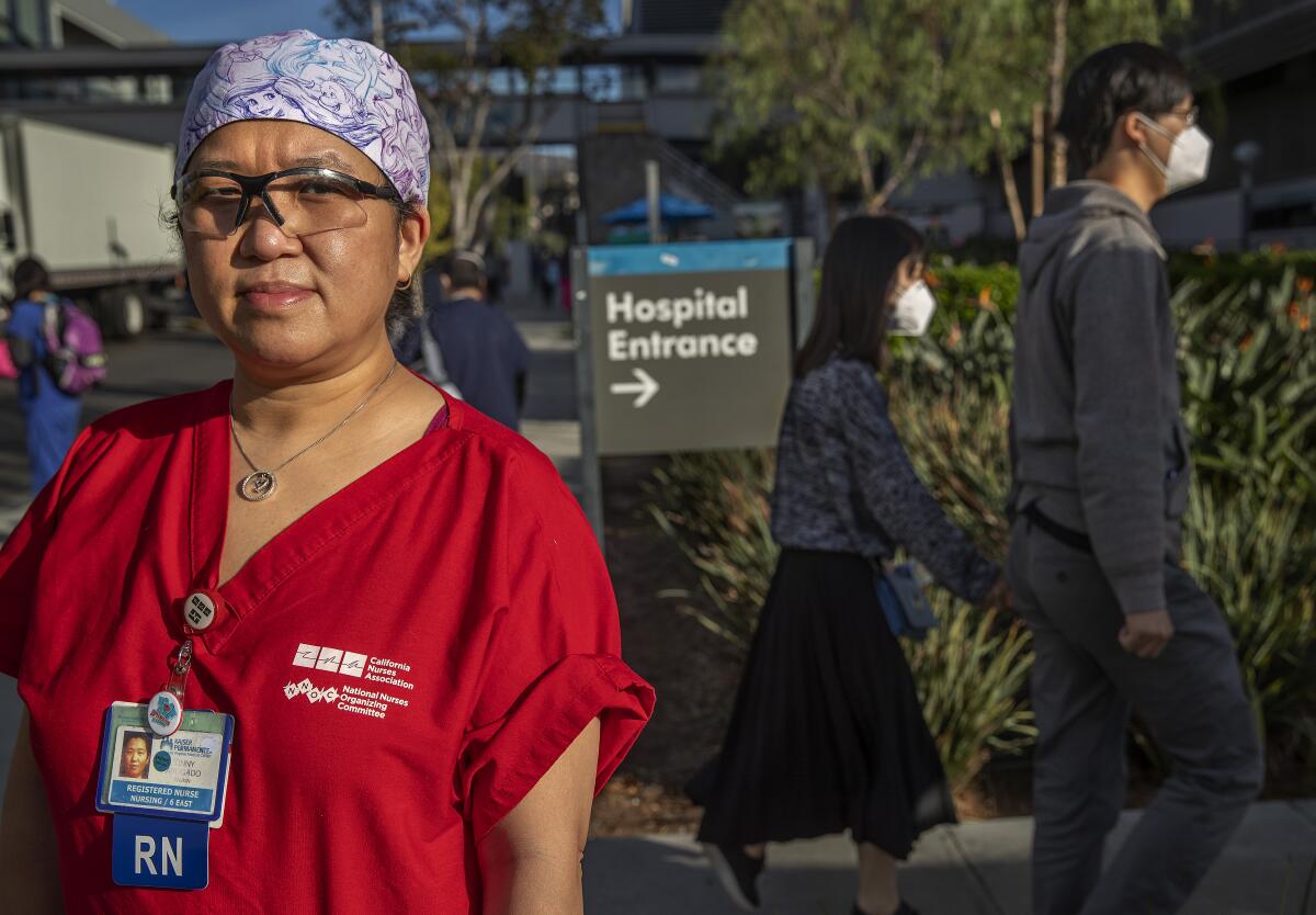 Tinny Abogado, in scrubs, outside Kaiser Permanente L.A. Medical Center. Behind her, people in masks enter the hospital.