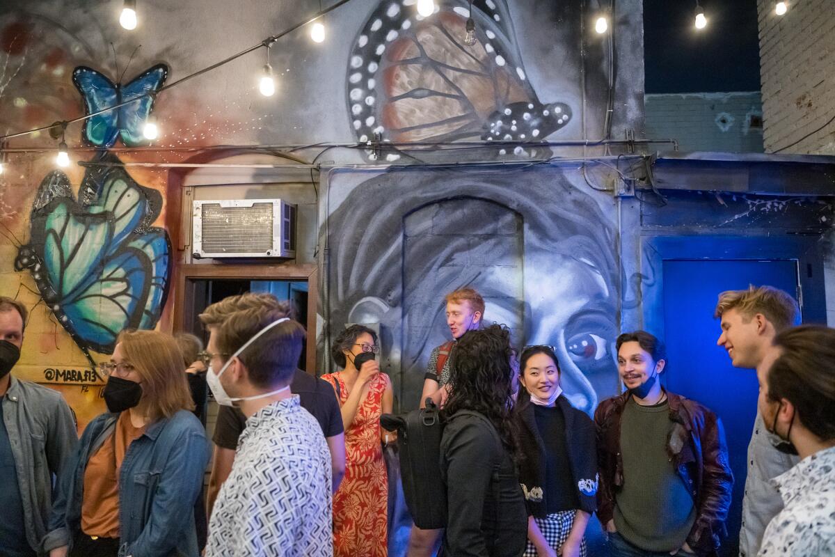 People stand in front of a brightly painted mural. 