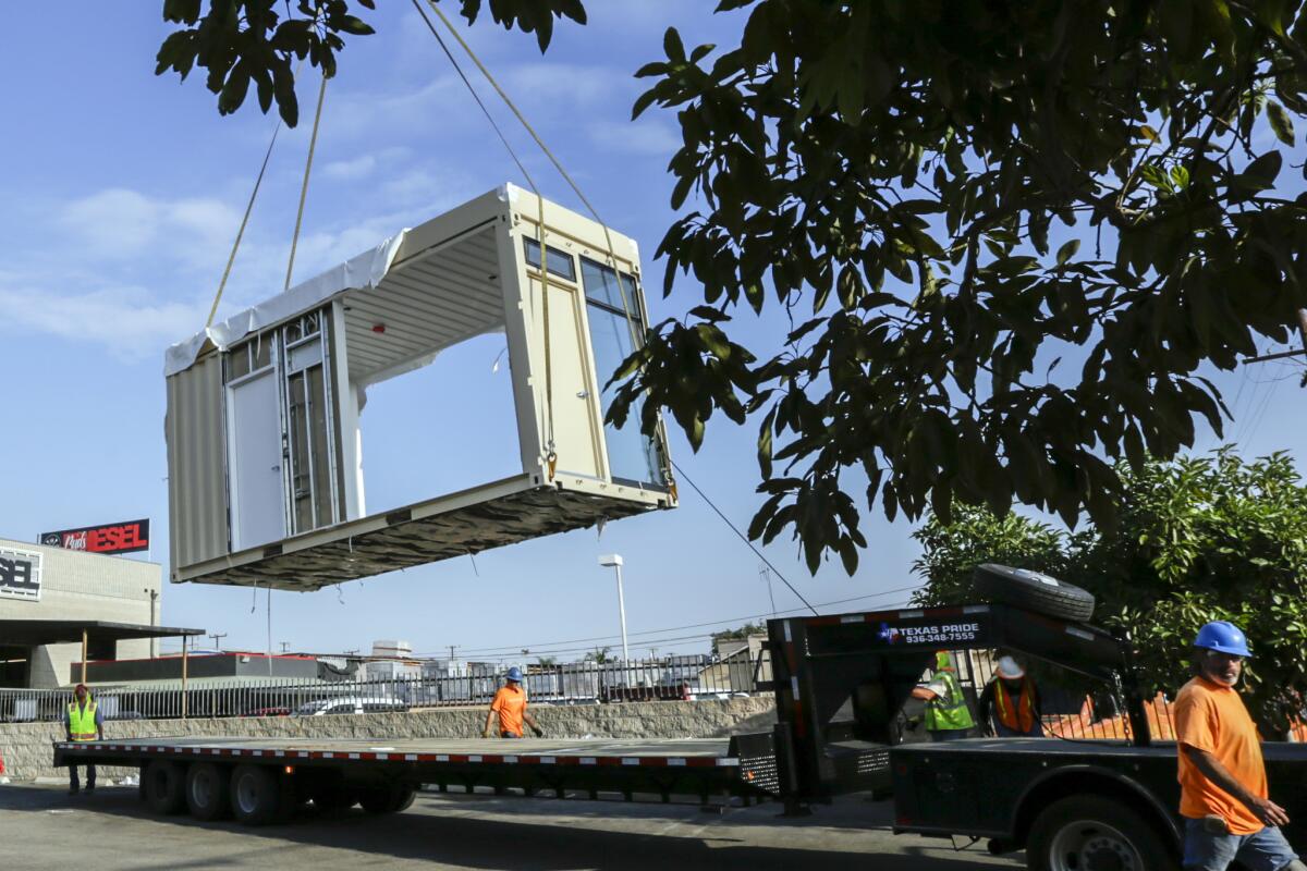 A shipping container that is being converted to housing for homeless people is lifted off a truck Wednesday in Orange County's Midway City.