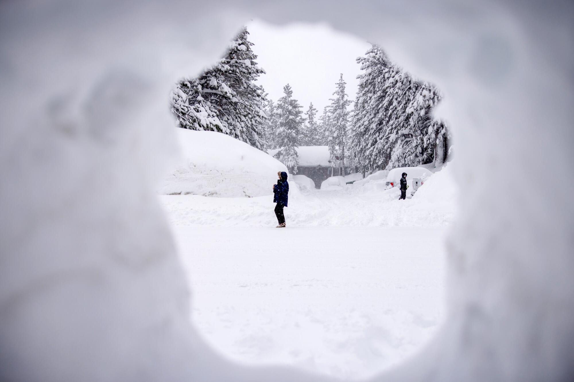 A person is framed through a hole in a snow bank in Mammoth Lakes. 